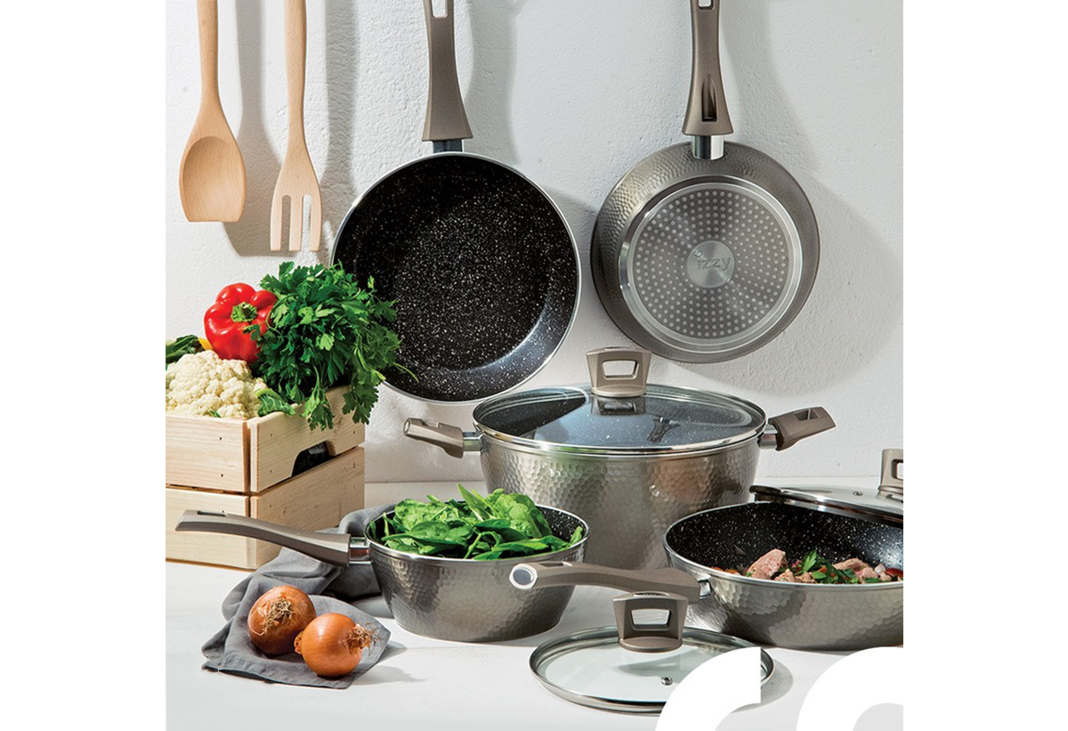 Απεικονίζεται ο πάγκος κουζίνας στον οποίο είναι τοποθετημένα σκέυη Izzy, όπως κατσαρόλες και τηγάνια, ενώ από πάνω κρέμονται τηγάνια Izzy καθώς και κουτάλα και πιρούνα.